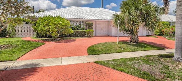 view of front of house featuring a front lawn, curved driveway, and a tile roof