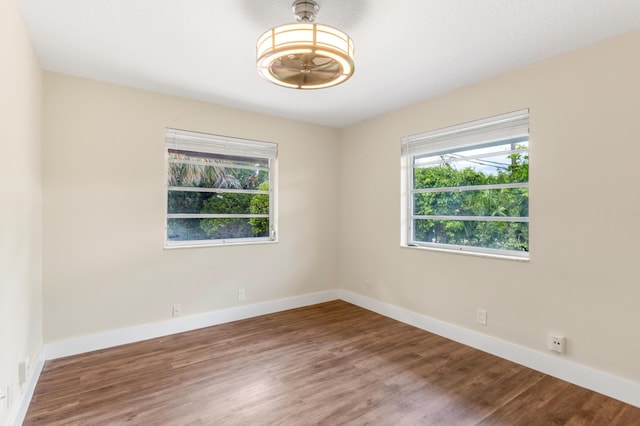 unfurnished room featuring wood finished floors, baseboards, and a wealth of natural light