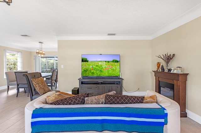 living room featuring visible vents, baseboards, light wood-type flooring, and an inviting chandelier