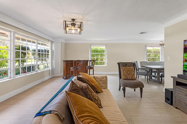 living room featuring a chandelier, a textured ceiling, a healthy amount of sunlight, and baseboards