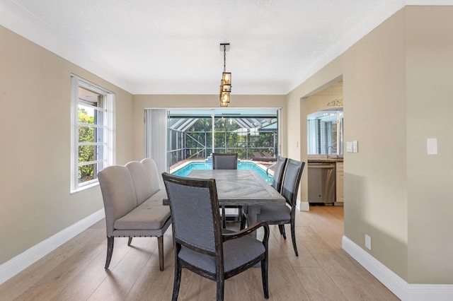 dining area featuring light wood-style flooring, baseboards, and a sunroom