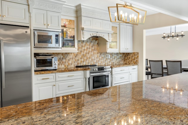 kitchen with dark stone countertops, stainless steel appliances, decorative backsplash, a notable chandelier, and a toaster
