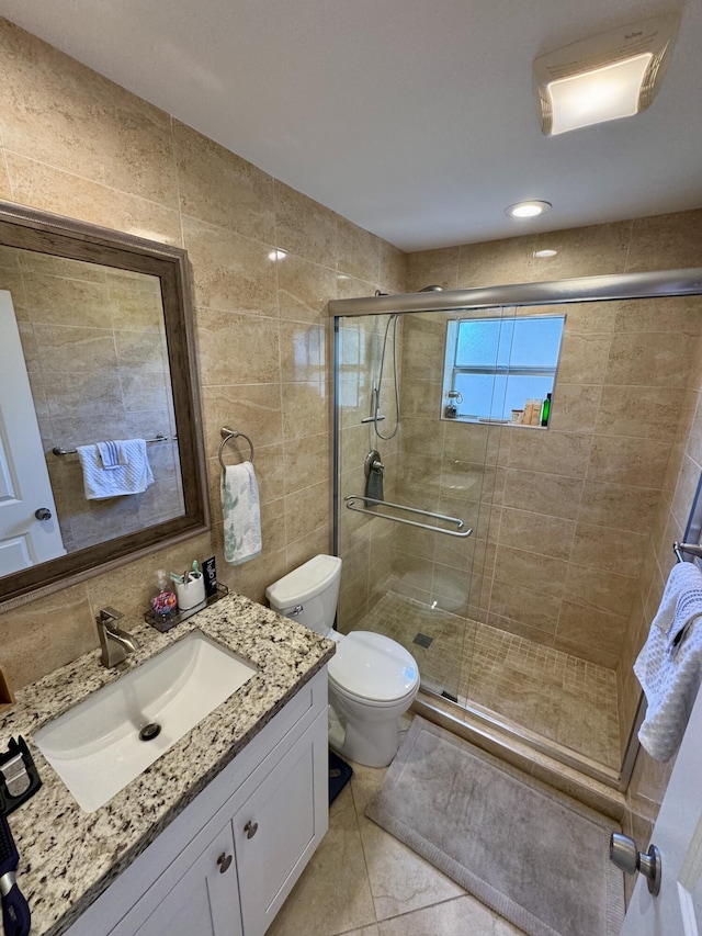 bathroom featuring tile walls, toilet, a stall shower, and vanity