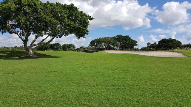 surrounding community featuring golf course view and a yard