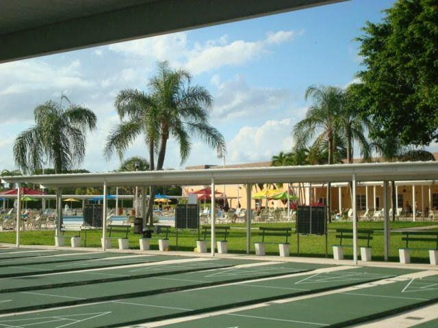 view of community featuring shuffleboard and a yard