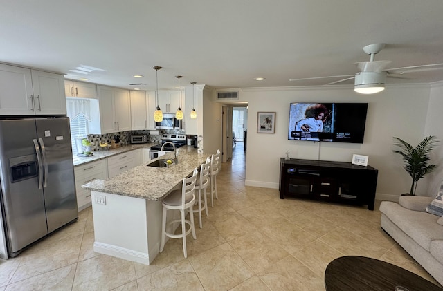 kitchen with tasteful backsplash, light stone countertops, a kitchen breakfast bar, appliances with stainless steel finishes, and visible vents
