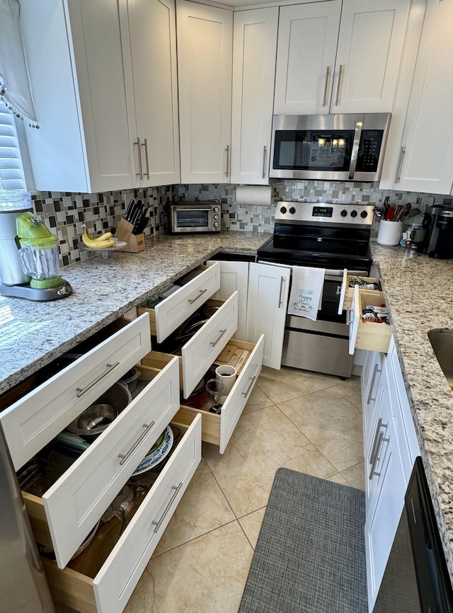 kitchen with white cabinetry, light tile patterned floors, stainless steel appliances, and tasteful backsplash
