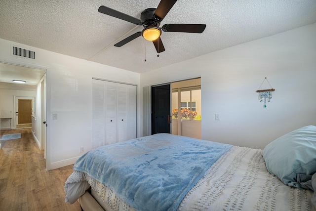bedroom featuring a textured ceiling, visible vents, baseboards, and light wood-type flooring