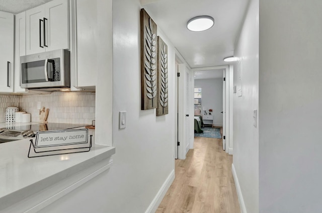 hall with baseboards and light wood finished floors
