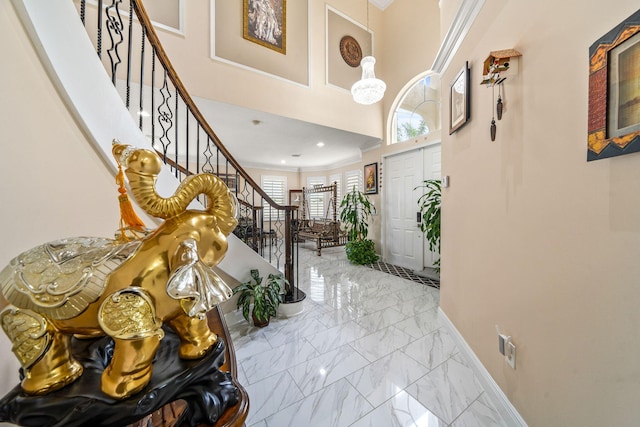 foyer entrance with marble finish floor, baseboards, crown molding, and stairs