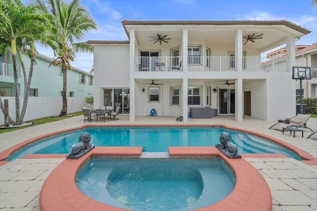back of house featuring stucco siding, a balcony, ceiling fan, and fence