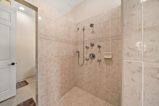 bathroom featuring a tile shower, visible vents, and crown molding