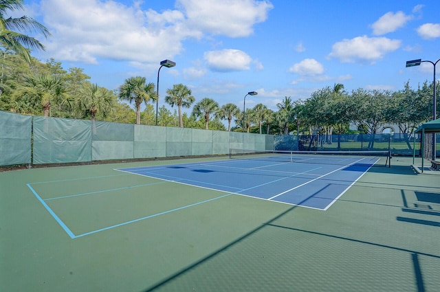 view of tennis court featuring community basketball court and fence
