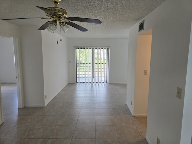 unfurnished room with a textured ceiling, ceiling fan, visible vents, and light tile patterned floors