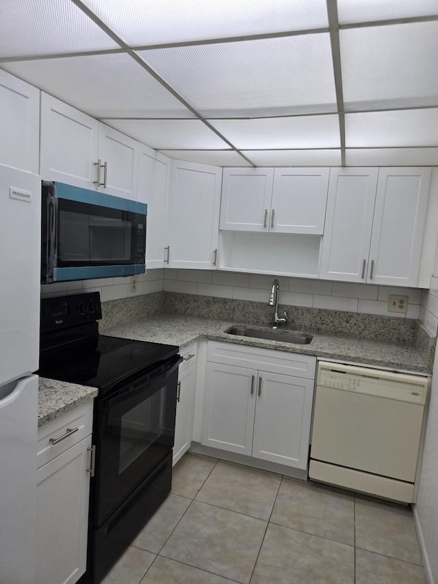 kitchen with a sink, black range with electric cooktop, light tile patterned floors, and dishwasher
