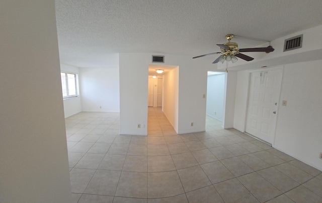 unfurnished room featuring visible vents, a textured ceiling, ceiling fan, and light tile patterned floors