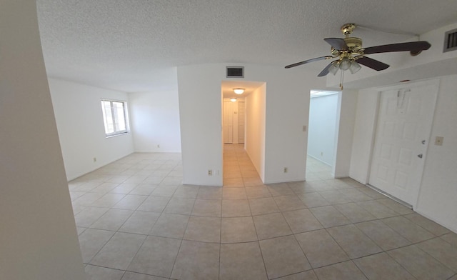 empty room featuring light tile patterned floors, ceiling fan, a textured ceiling, and visible vents