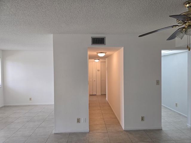 spare room with a textured ceiling, ceiling fan, visible vents, and light tile patterned floors