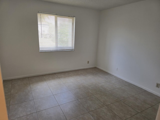 tiled empty room featuring baseboards
