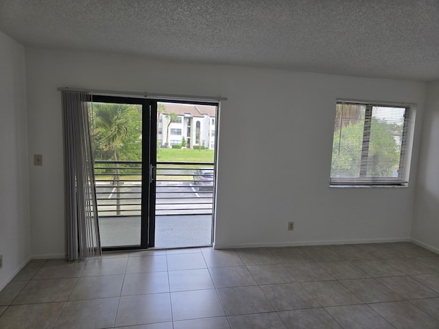 tiled spare room with a textured ceiling and baseboards