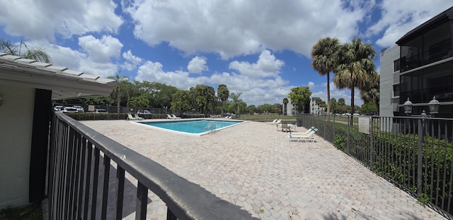 community pool with fence and a patio area