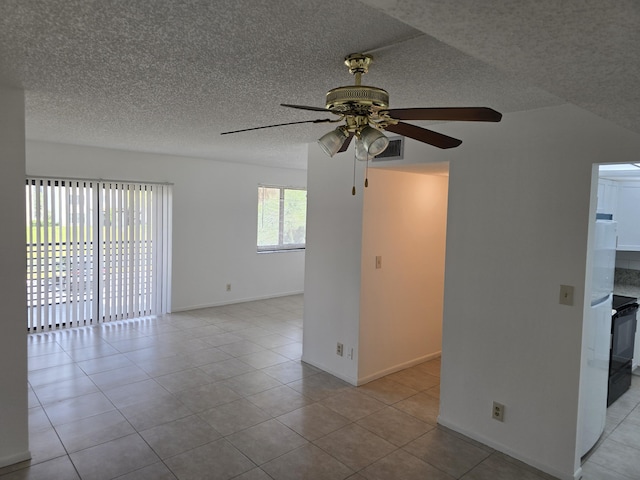 empty room with baseboards, a textured ceiling, ceiling fan, and light tile patterned flooring