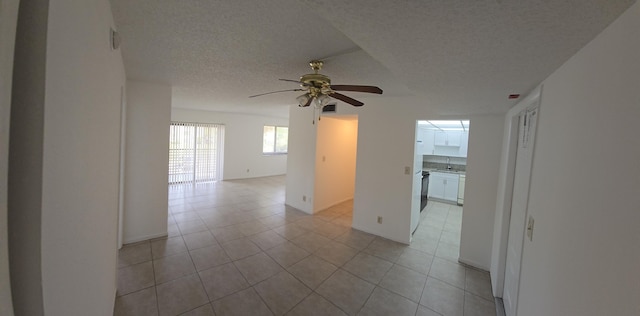 empty room featuring baseboards, a textured ceiling, ceiling fan, and light tile patterned floors