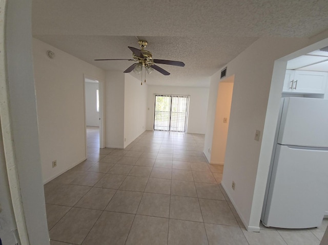 spare room featuring visible vents, light tile patterned flooring, baseboards, ceiling fan, and a textured ceiling