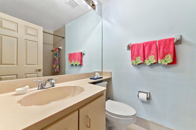 bathroom with a shower, vanity, toilet, tile patterned floors, and visible vents