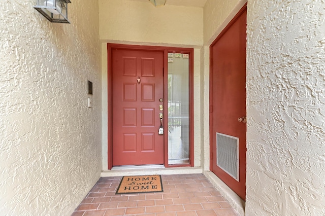 view of exterior entry with visible vents and stucco siding