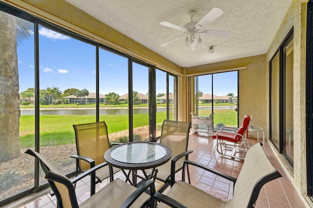 sunroom featuring a water view, outdoor dining area, and a ceiling fan