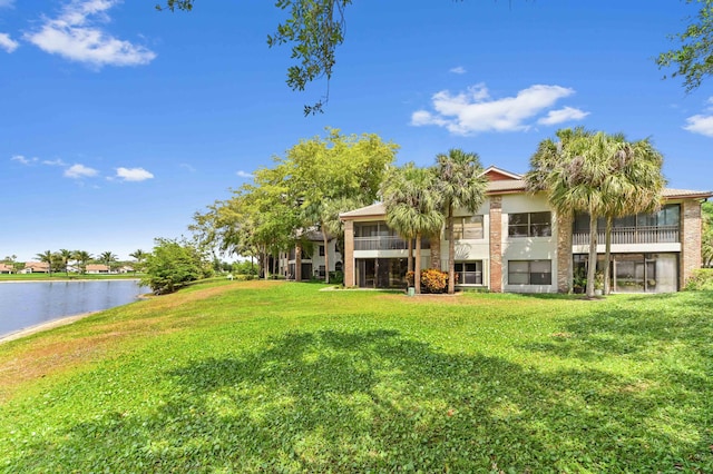view of yard featuring a sunroom and a water view