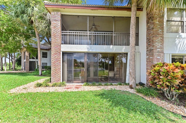 rear view of property featuring brick siding, ceiling fan, and a yard
