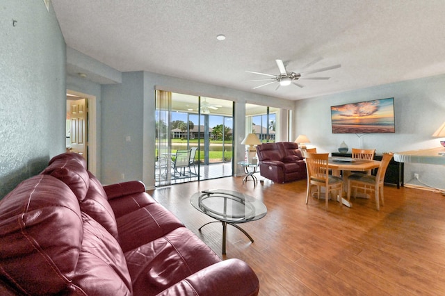 living area featuring a textured wall, a textured ceiling, ceiling fan, and wood finished floors