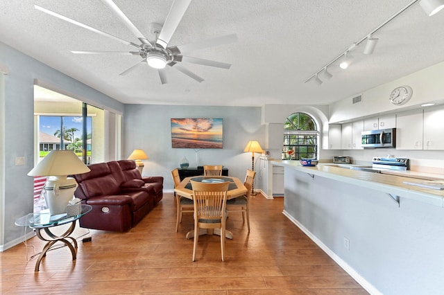 dining room with a textured ceiling, a wealth of natural light, visible vents, and light wood finished floors