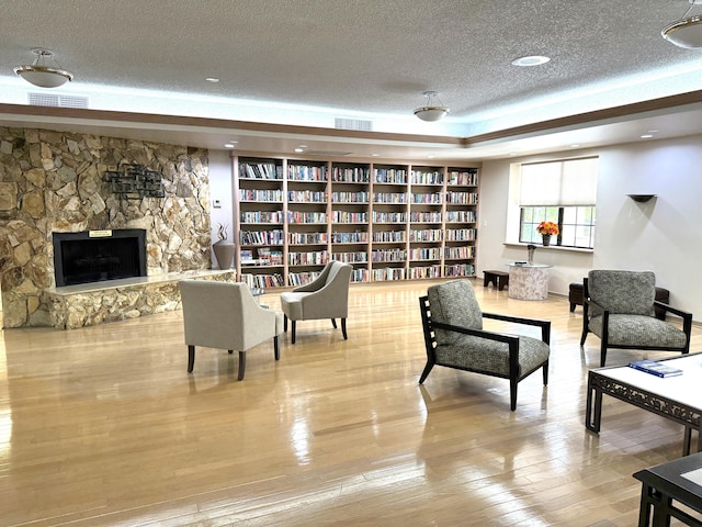 3779 Carambola Cir N Unit 28102, Coconut Creek, FL 33066 - living area featuring a textured ceiling, hardwood / wood-style floors, a fireplace, a raised ceiling, and wall of books