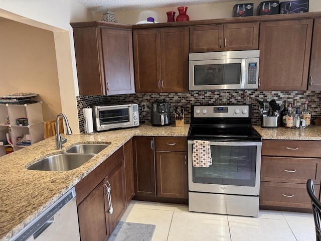 3779 Carambola Cir N Unit 28102, Coconut Creek, FL 33066 - kitchen with appliances with stainless steel finishes, a sink, light tile patterned floors, backsplash, and a textured ceiling