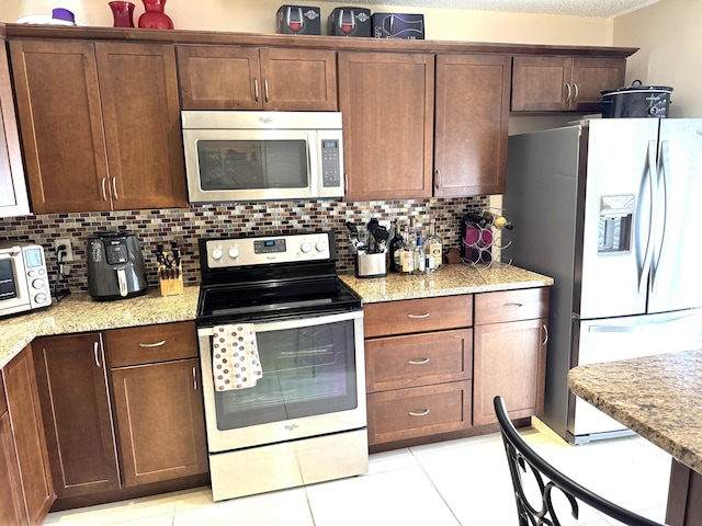 3779 Carambola Cir N Unit 28102, Coconut Creek, FL 33066 - kitchen featuring appliances with stainless steel finishes, tasteful backsplash, light tile patterned flooring, and light stone countertops