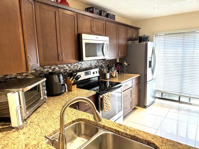 3779 Carambola Cir N Unit 28102, Coconut Creek, FL 33066 - kitchen with appliances with stainless steel finishes, a sink, tasteful backsplash, a textured ceiling, and light stone counters