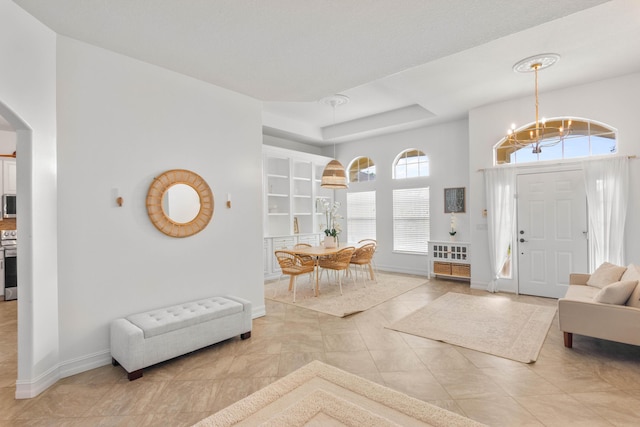 foyer with a chandelier, arched walkways, baseboards, and light tile patterned flooring