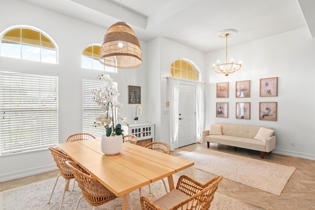 dining space with a chandelier, baseboards, and a towering ceiling