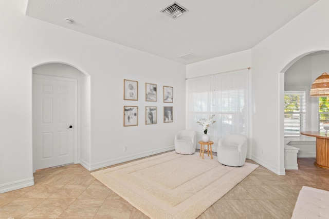 living area with arched walkways, baseboards, and tile patterned flooring
