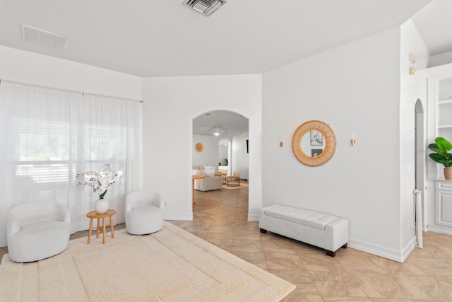 living area with arched walkways, light tile patterned floors, and baseboards