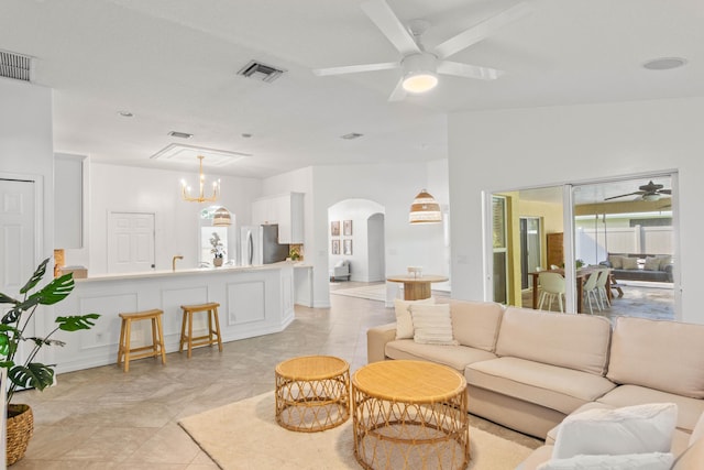 living area featuring ceiling fan, arched walkways, and a chandelier