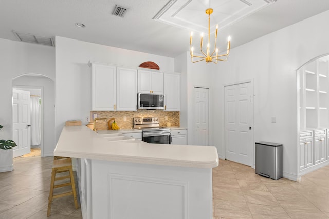 kitchen with appliances with stainless steel finishes, arched walkways, a sink, decorative backsplash, and light countertops