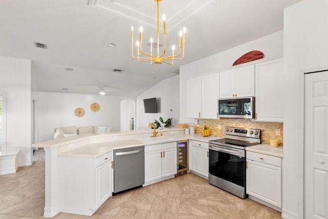 kitchen featuring appliances with stainless steel finishes, wine cooler, a peninsula, backsplash, and lofted ceiling