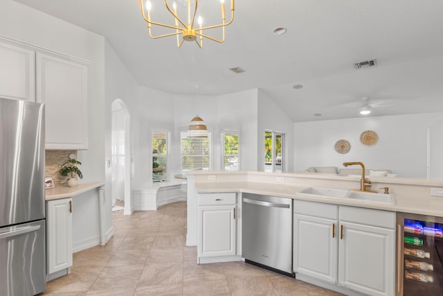kitchen featuring stainless steel appliances, beverage cooler, a sink, white cabinets, and light countertops