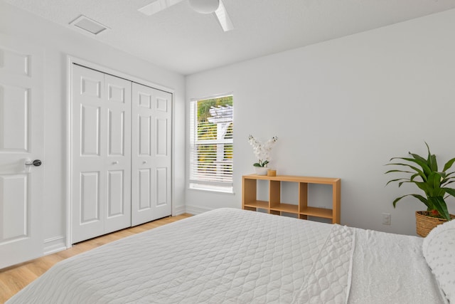 bedroom with wood finished floors, a closet, ceiling fan, and baseboards