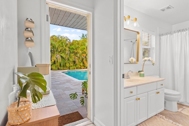 bathroom featuring toilet, plenty of natural light, vanity, and a shower with curtain