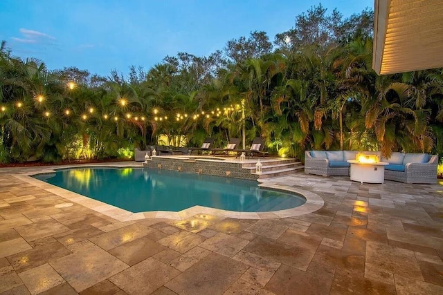 outdoor pool featuring a patio and an outdoor living space with a fire pit